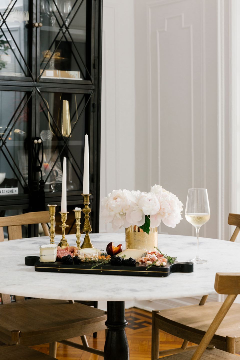 Modern black and white marble dining setup with gold candlesticks, white florals, and contemporary elegance
