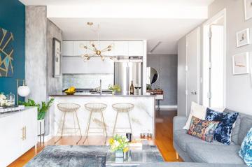 Bright open-concept kitchen with teal accent wall, white cabinetry, and warm wood flooring creating contemporary coastal vibes