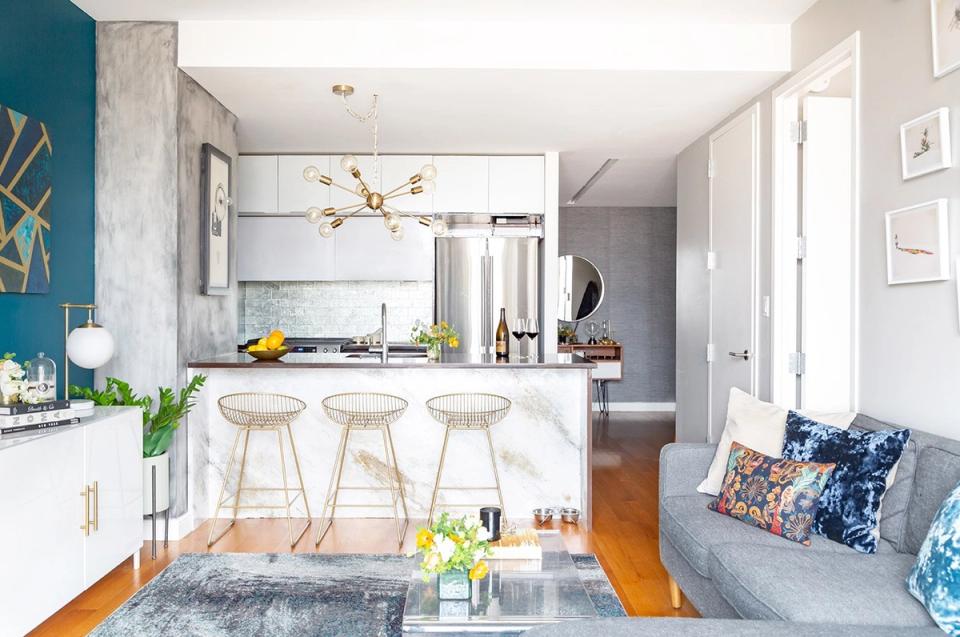 Bright open-concept kitchen with teal accent wall, white cabinetry, and warm wood flooring creating contemporary coastal vibes