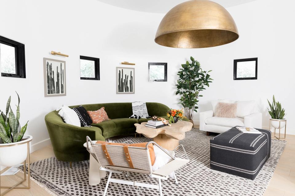 Modern eclectic living room with olive green curved sofa, brass pendant, and gallery wall