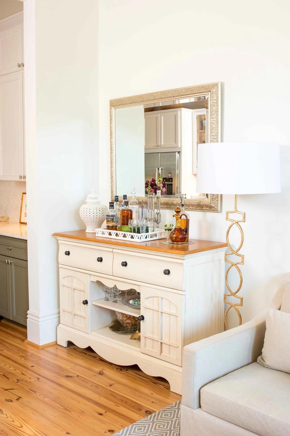 Coastal farmhouse bathroom vanity with cream cabinetry, wood top, and gold-framed mirror