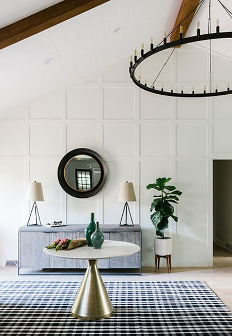 Bright farmhouse entryway with shiplap walls, exposed wood beam, black metal chandelier, and black-and-white gingham runner