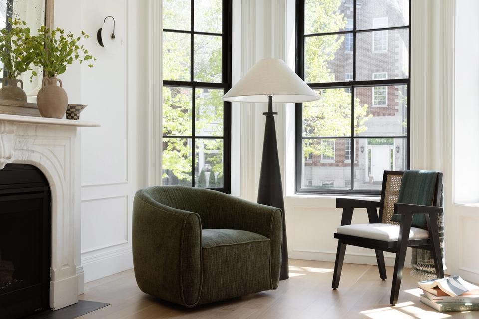 Modern living room with olive green swivel chair, fireplace, and floor-to-ceiling windows