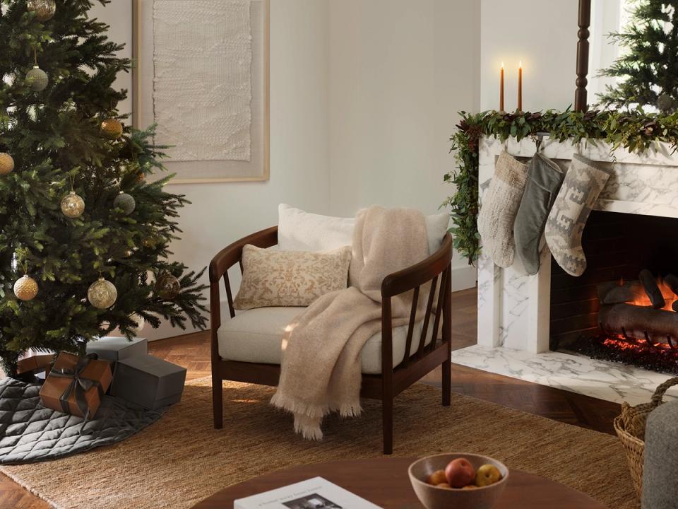 Warm traditional holiday living room with fireplace, evergreen garland, and cozy seating