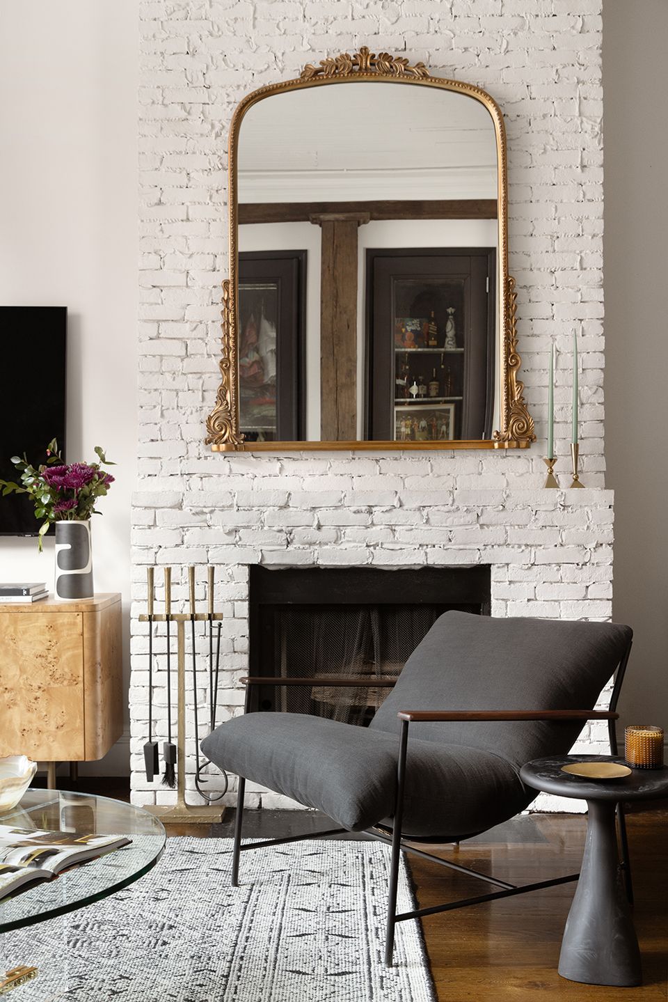 Modern Victorian style with white brick, gold-trimmed mirror, and contemporary seating