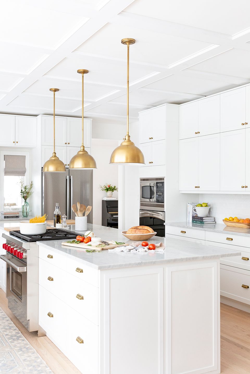Modern kitchen with trio of brass dome pendants over white island