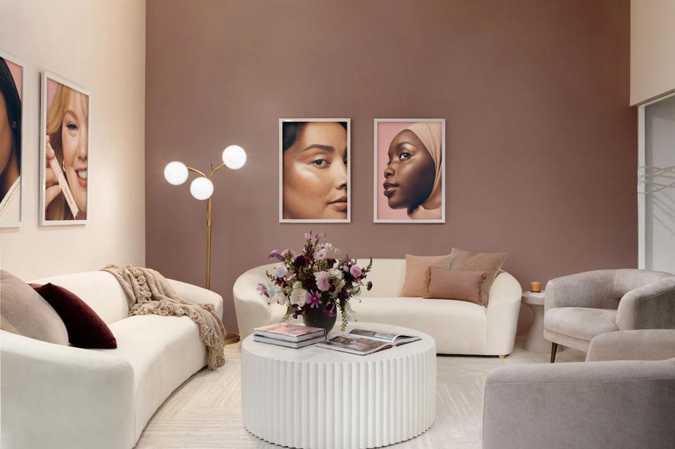 Warm modern living room with mauve accent wall, cream seating, and portrait gallery display