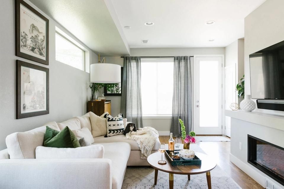 Bright, minimalist living room with cream furnishings, soft gray accents, and floor-to-ceiling windows creating an airy, serene atmosphere
