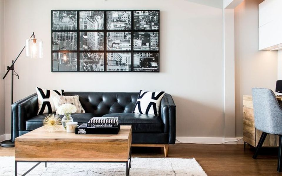 Industrial modern living room showcasing black leather sofa, geometric pillow styling, wooden table, and grid wall art