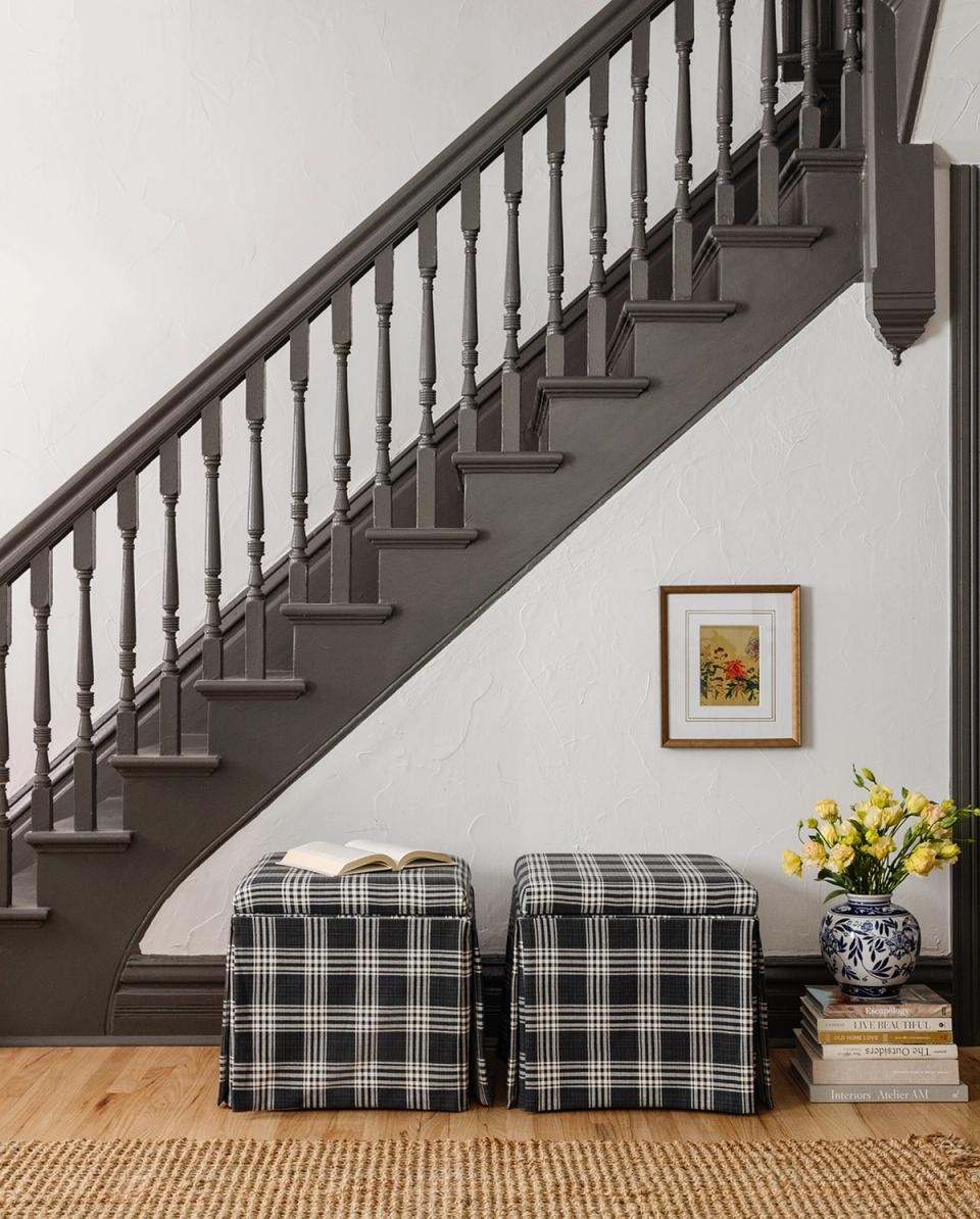 Traditional stair landing with black-and-white plaid ottomans, gray railing, and understated cottage charm