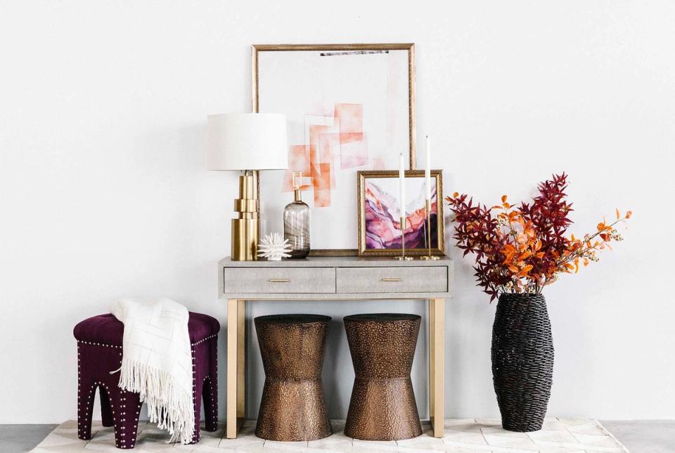 Glam entryway console with burgundy accents, brass frames, and dried florals