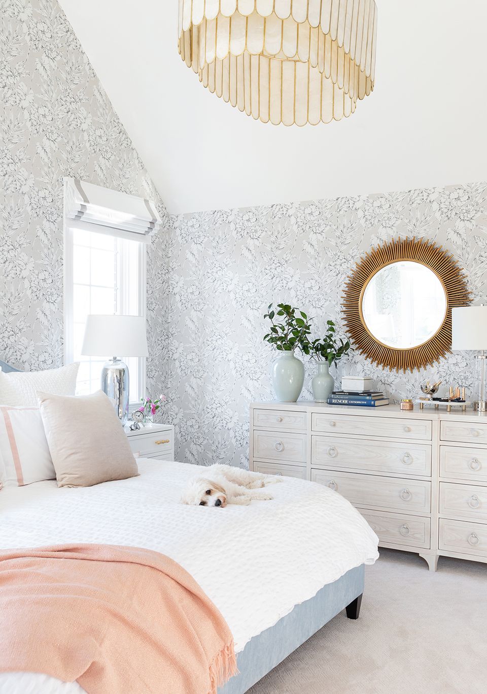 Soft contemporary bedroom with patterned wallpaper, brass pendant light, pink bedding, and serene neutral color scheme