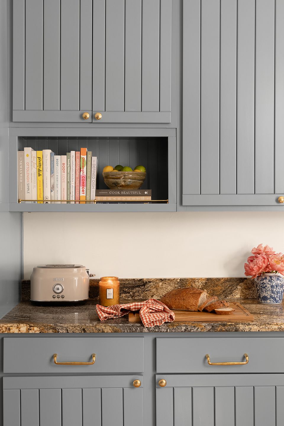Modern farmhouse cabinetry detail in soft gray with brass hardware, open shelving, and warm wood countertop
