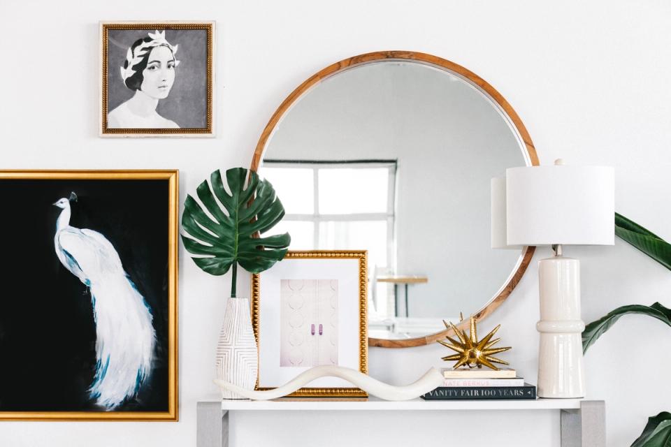 Modern entryway with botanical art, round wood mirror, white accents, and green plants