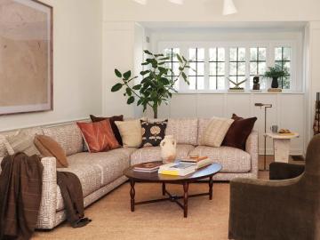 Warm, layered living room with beige sectional, terracotta pillows, and mid-tone wood coffee table