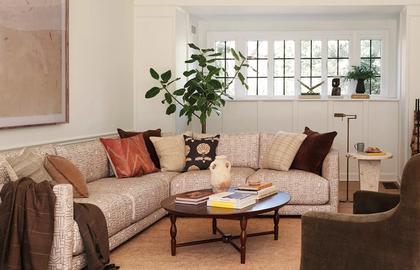 Warm, layered living room with beige sectional, terracotta pillows, and mid-tone wood coffee table