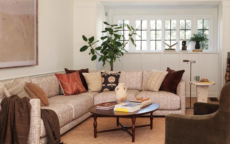 Warm, layered living room with beige sectional, terracotta pillows, and mid-tone wood coffee table