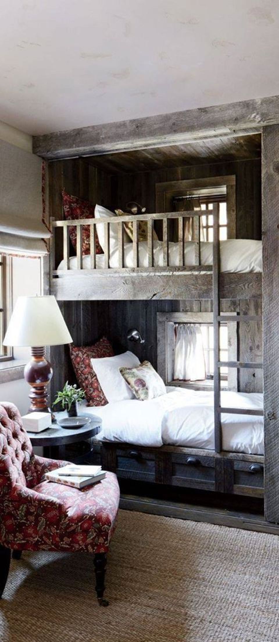 Rustic loft bedroom with weathered wood beams, burgundy accents, and cozy layered bedding