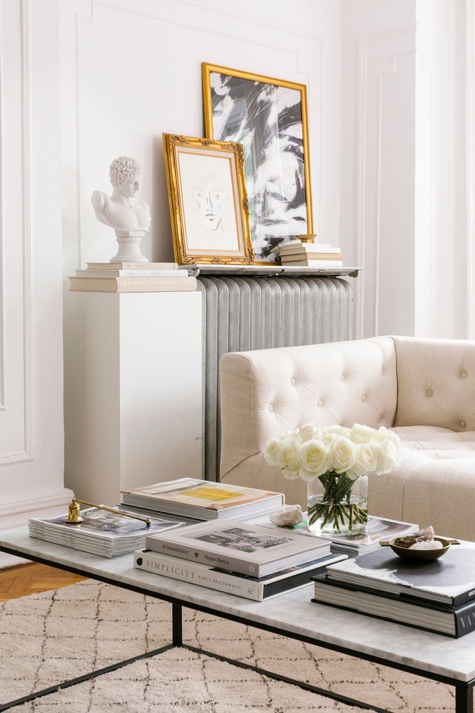 Minimalist modern space with gold-framed black and white portraits, white bust sculpture, and neutral color palette