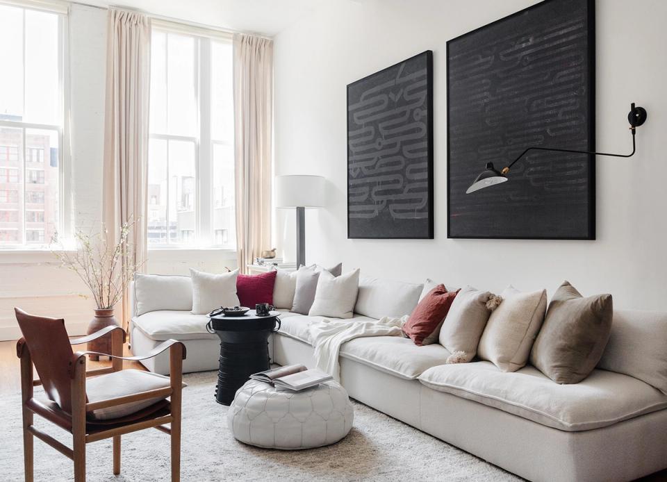 Contemporary space with cream sectional, black accent wall art, and warm wood furnishings