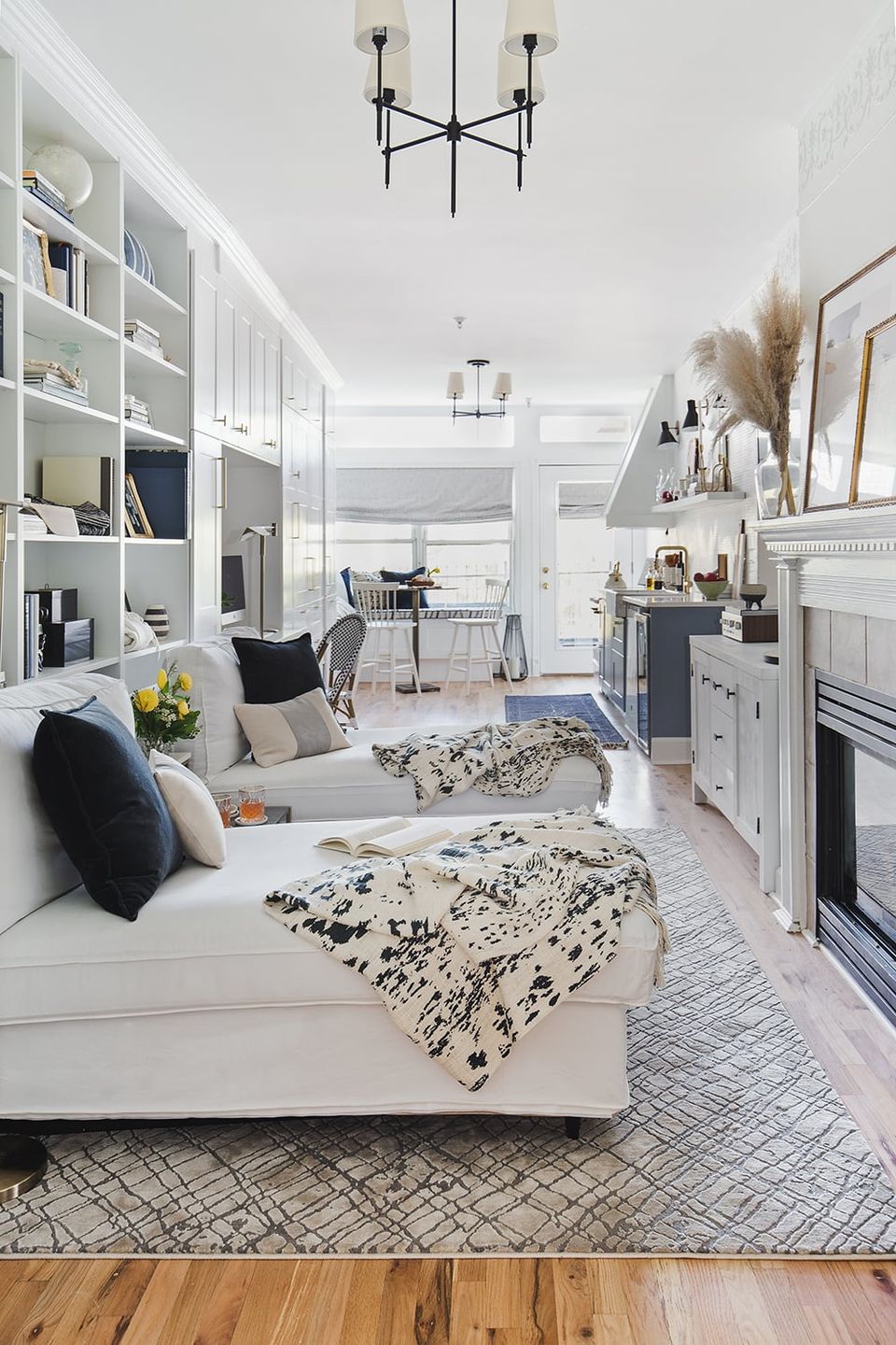Contemporary white living space with built-in shelving, crisp navy accents, geometric patterns, and modern pendant lighting in a clean, sophisticated layout