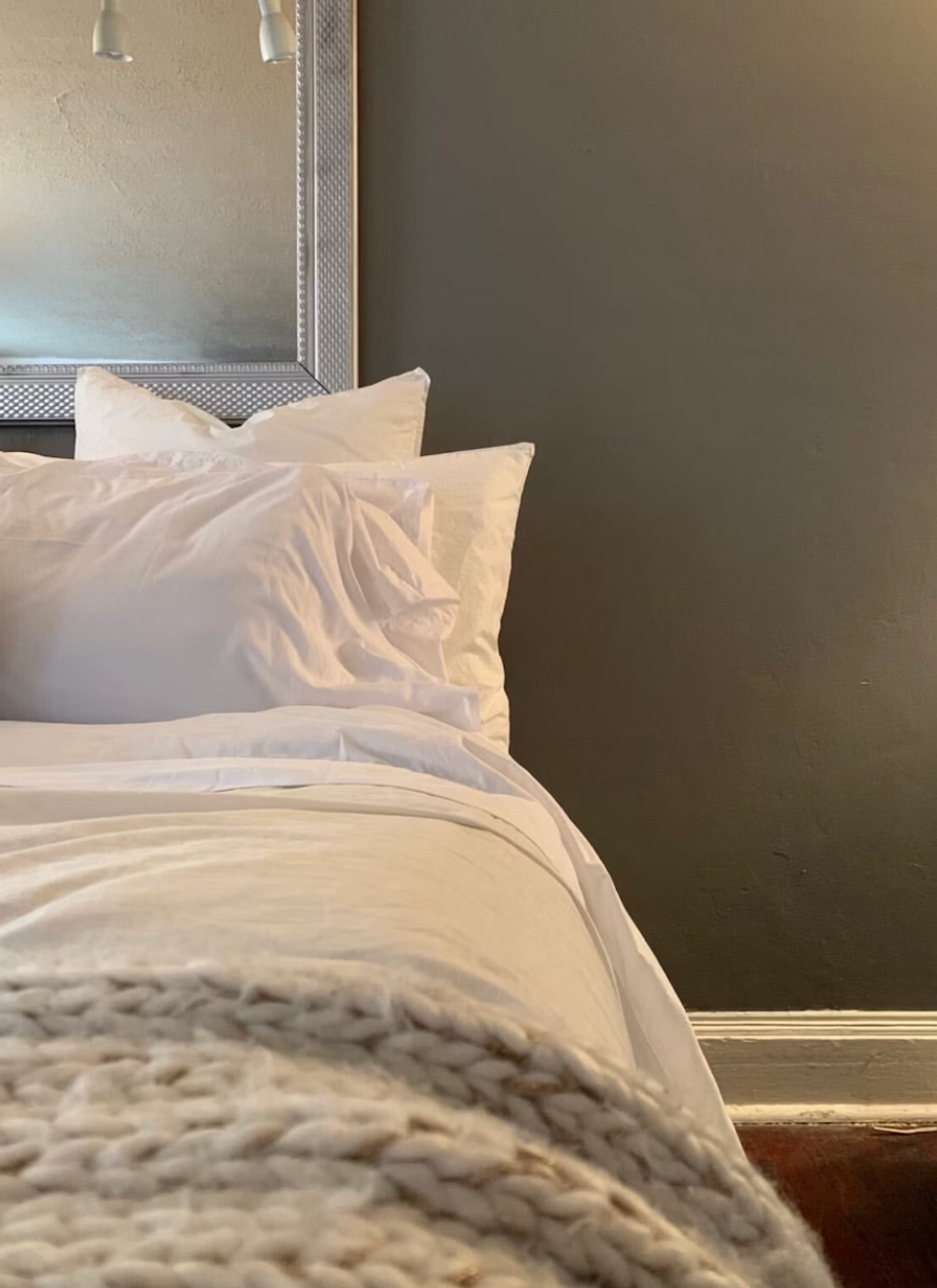 Serene bedroom corner with dark gray accent wall, cream bedding, and soft natural light for moody elegance