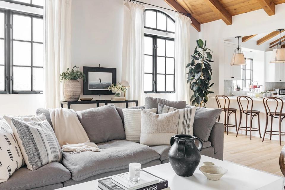 Scandinavian-inspired living room with light gray sofa, exposed beams, and bright windows