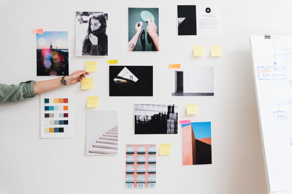 Minimalist vision board with black and white photography, color swatches, and neon sticky notes on white wall