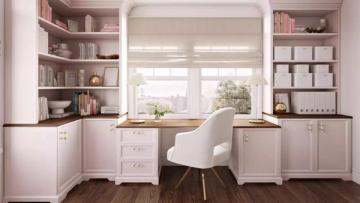 Soft pink built-in workspace with abundant shelving, cream chair, and warm wood accents in a bright, organized feminine office.