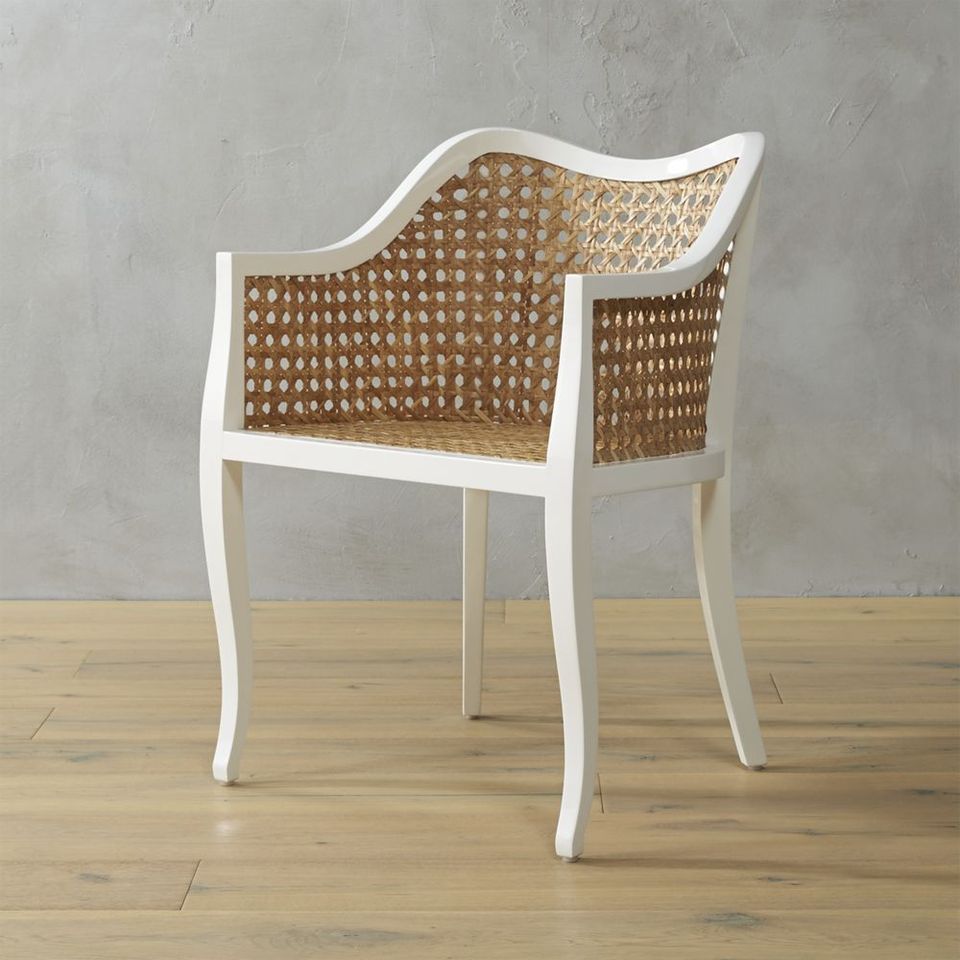 Contemporary rattan chair with white frame and woven seat back against neutral backdrop