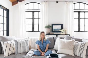 Bright coastal living room with layered neutral textiles, black-framed windows, and casual California aesthetic