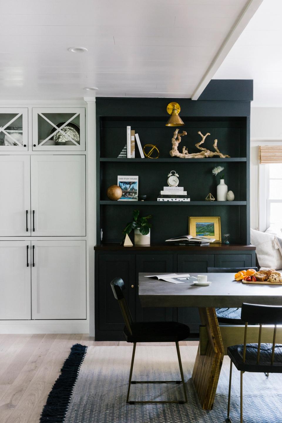 Contemporary kitchen with black built-in shelving, white cabinetry, and curated styling creating sophisticated contrast
