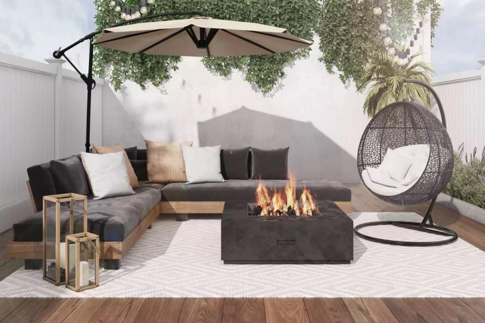 Relaxed courtyard setting with gray sectional, hanging chair, firepit, and lush greenery