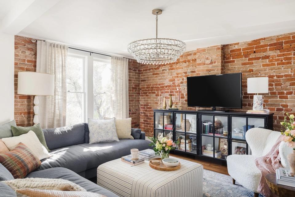 Industrial brick living room with crystal chandelier and navy sectional