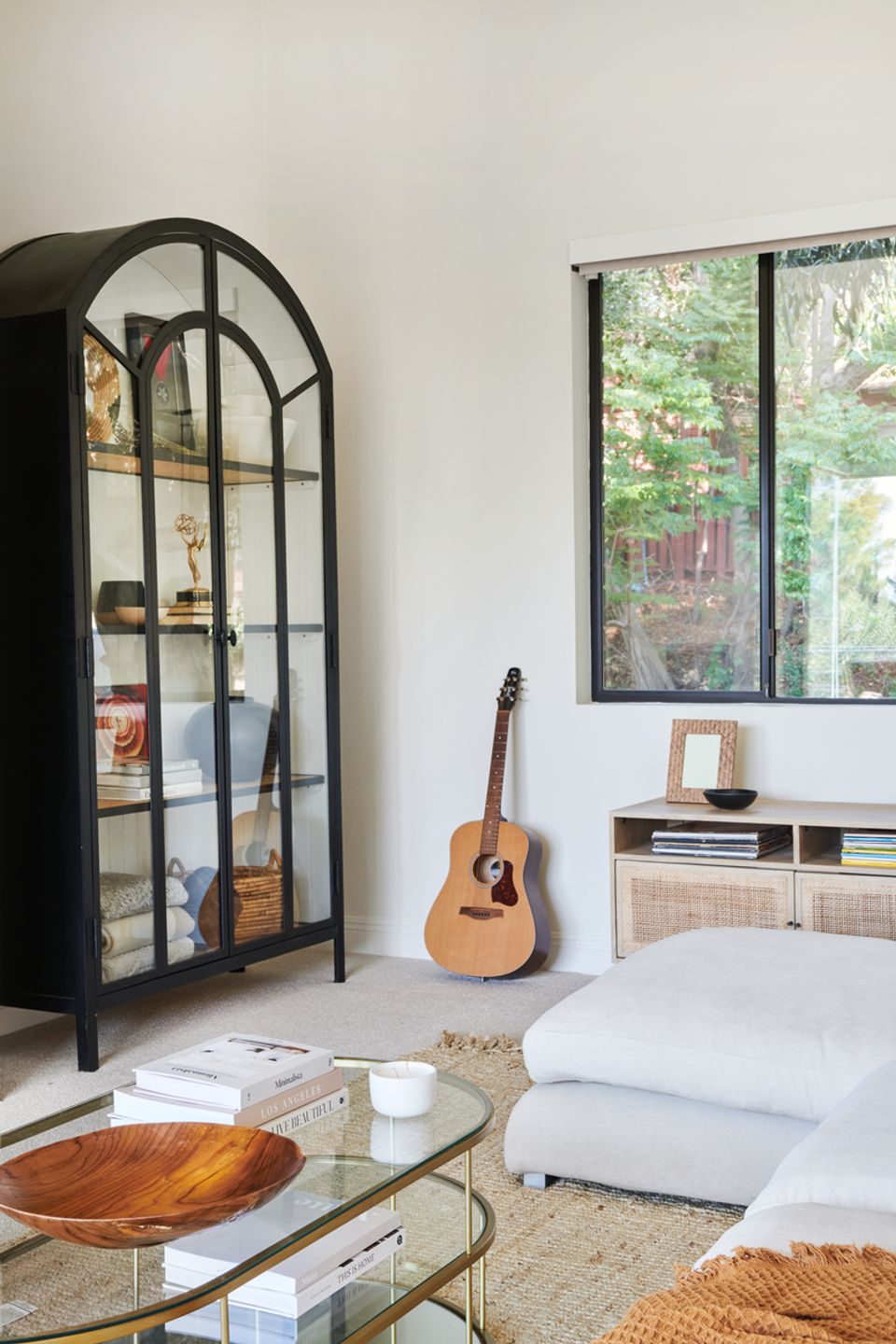 Serene cream living room with black metal display cabinet, natural wood accents, and peaceful earthy tones