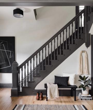 Modern farmhouse entryway with black staircase, white walls, and minimalist monochromatic palette