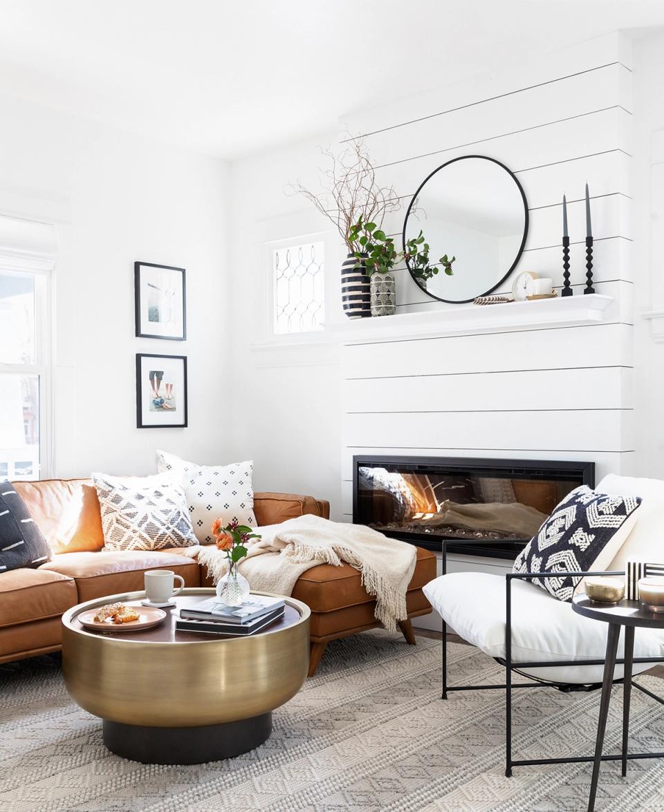 Contemporary boho lounge with caramel leather sofa, shiplap backdrop, brass accents, and minimalist wall décor