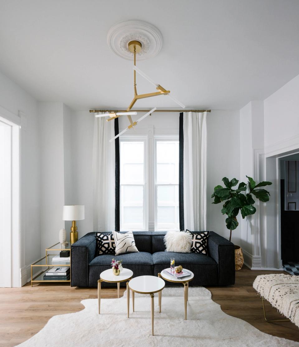 Contemporary minimalist space with charcoal sofa, brass fixtures, crisp white walls, and natural wood flooring for serene elegance