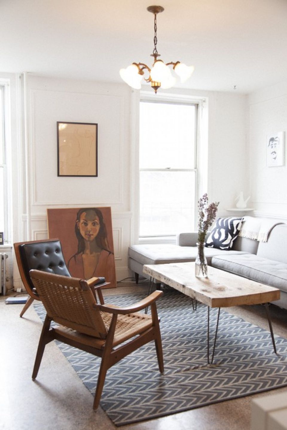 Mid-century modern living room with warm wood furniture, blue geometric rug, and vintage pendant lighting