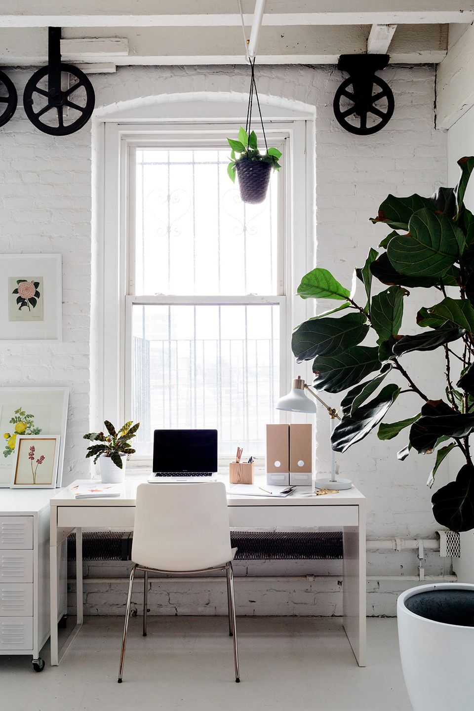 Scandinavian minimalist desk with lush greenery, industrial pulley shelving, and bright natural light