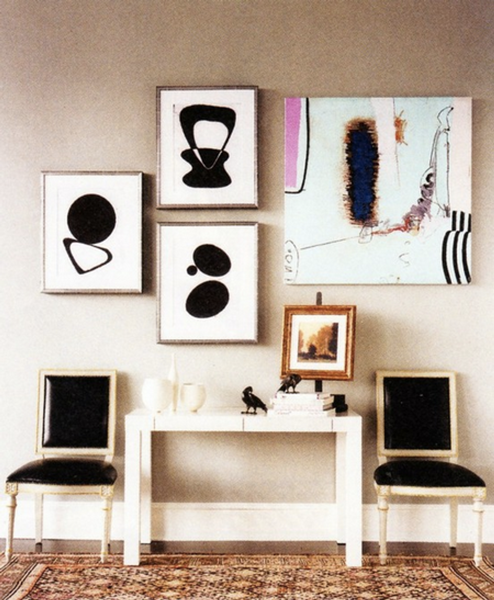 Minimalist gallery wall with abstract black line art above white Parsons desk and black velvet chairs