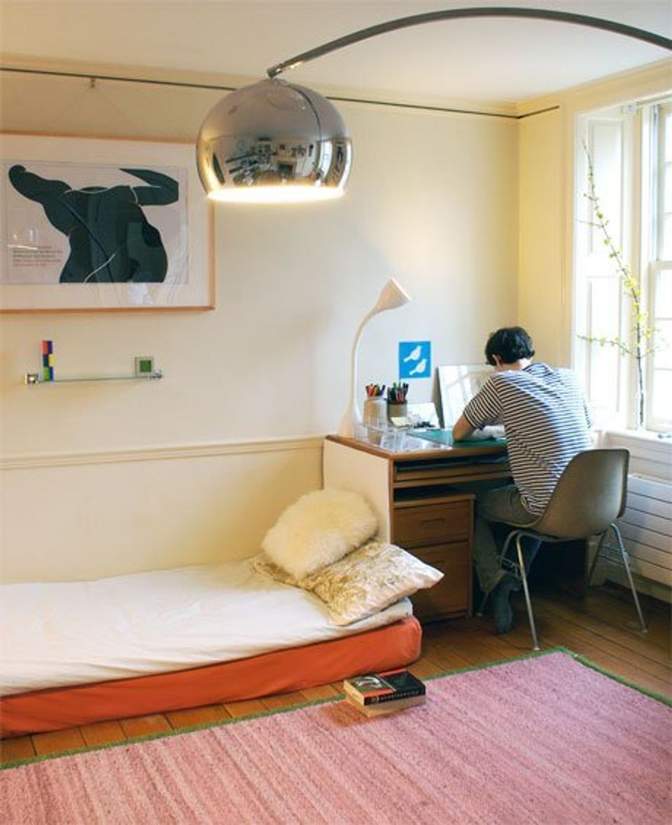 Bright minimalist dorm with yellow walls, arched pendant light, coral bed frame, and compact workspace by window