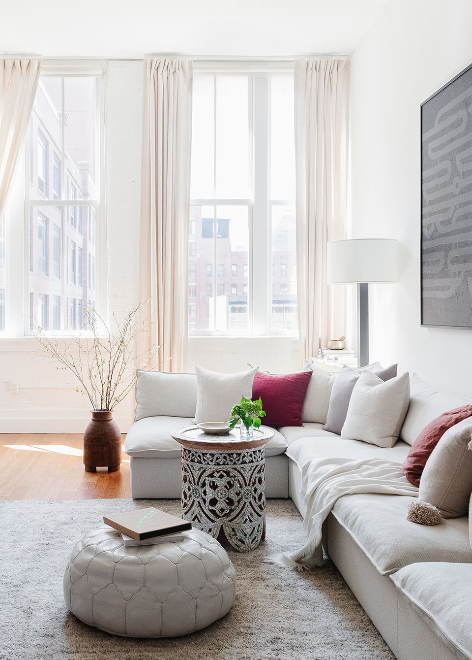 Soft contemporary lounge with neutral palette, burgundy pillows, and sculptural coffee table