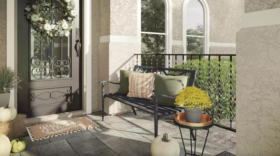 Transitional entryway with neutral stone palette, black arched door, and lush greenery creating serene elegance