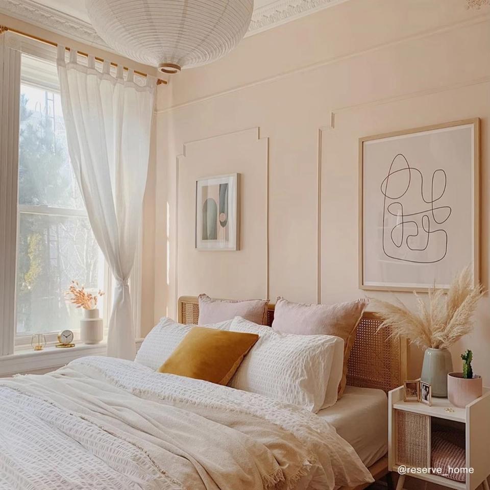 Soft, airy bedroom in warm blush pink with natural wood bed frame, linen bedding, and gentle minimalist Scandinavian charm.