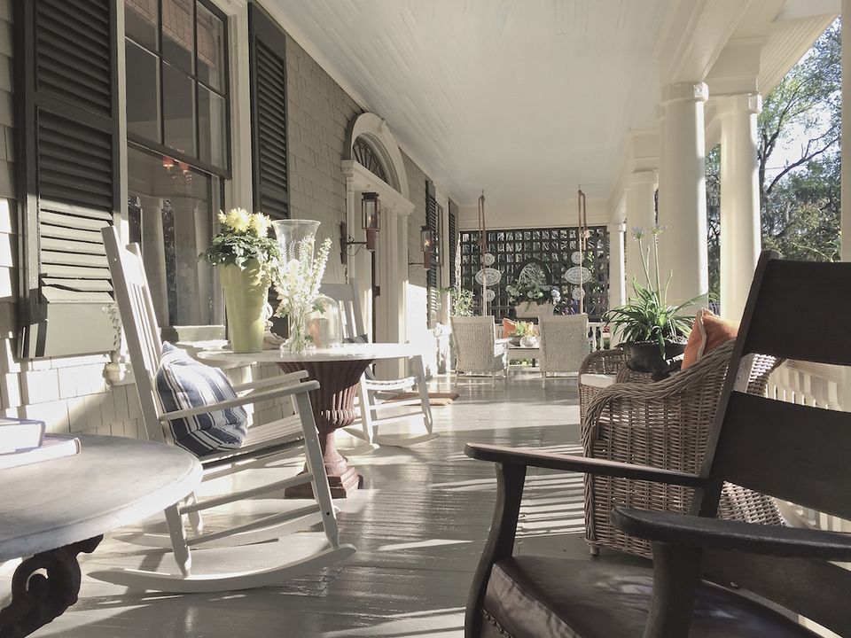 Bright, airy porch with black modern chairs, white flowers, and natural light creating a serene coastal aesthetic