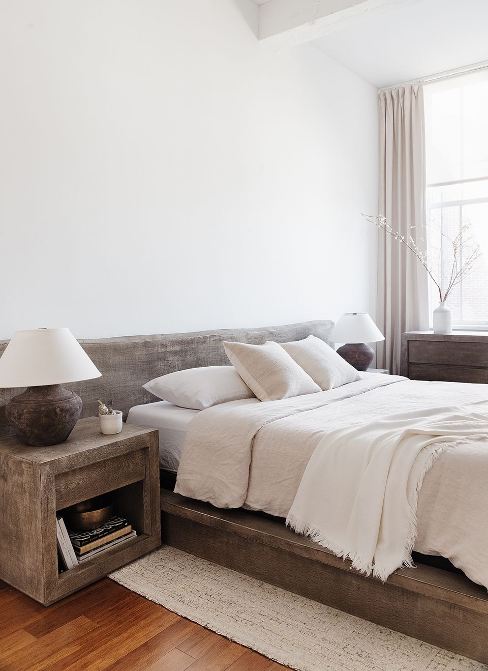 Contemporary rustic bedroom with weathered wood bed, neutral palette, and minimalist nightstand