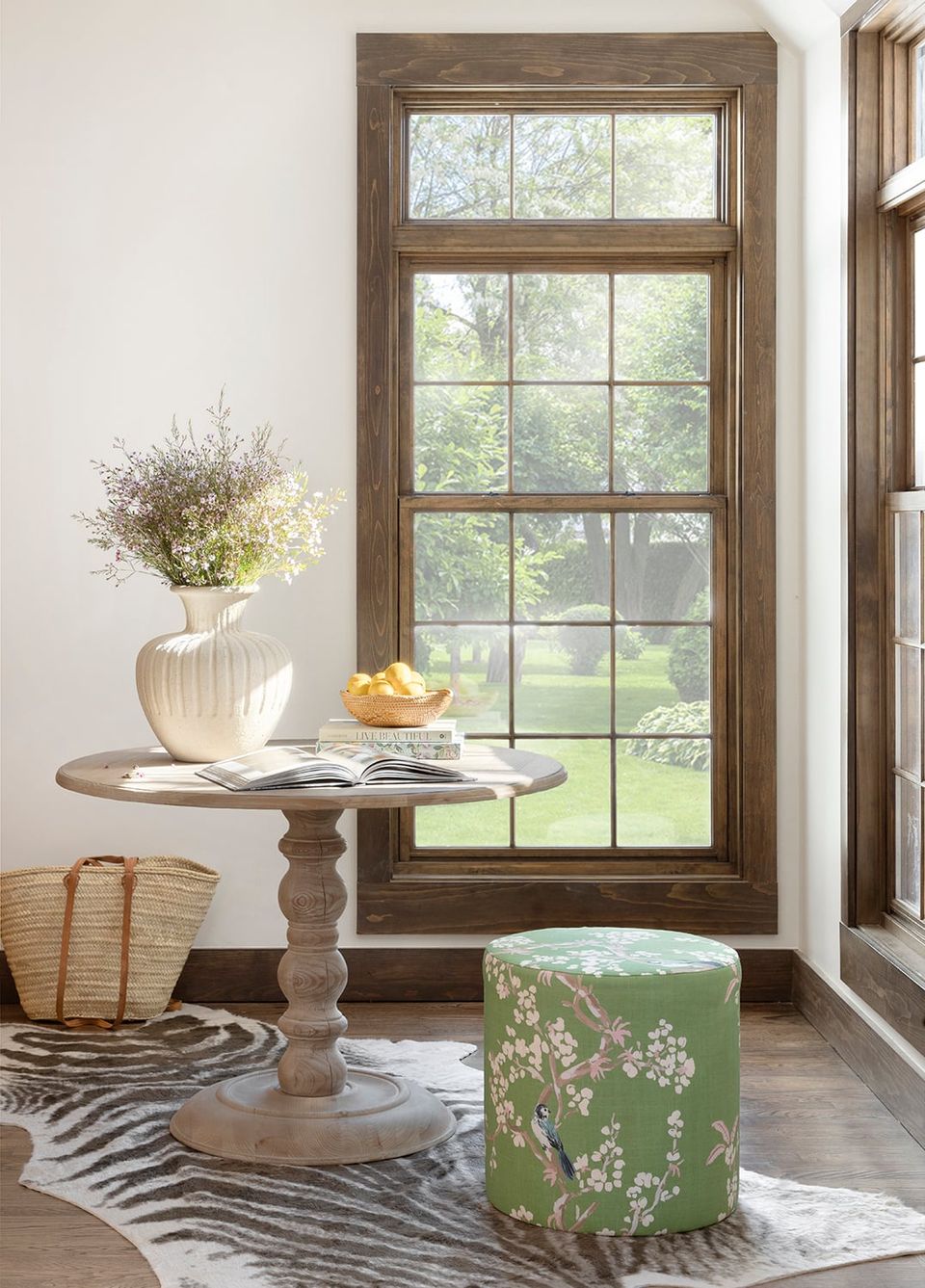 Farmhouse entryway blends natural wood window frame, round pedestal table, and botanical accents in warm neutral tones