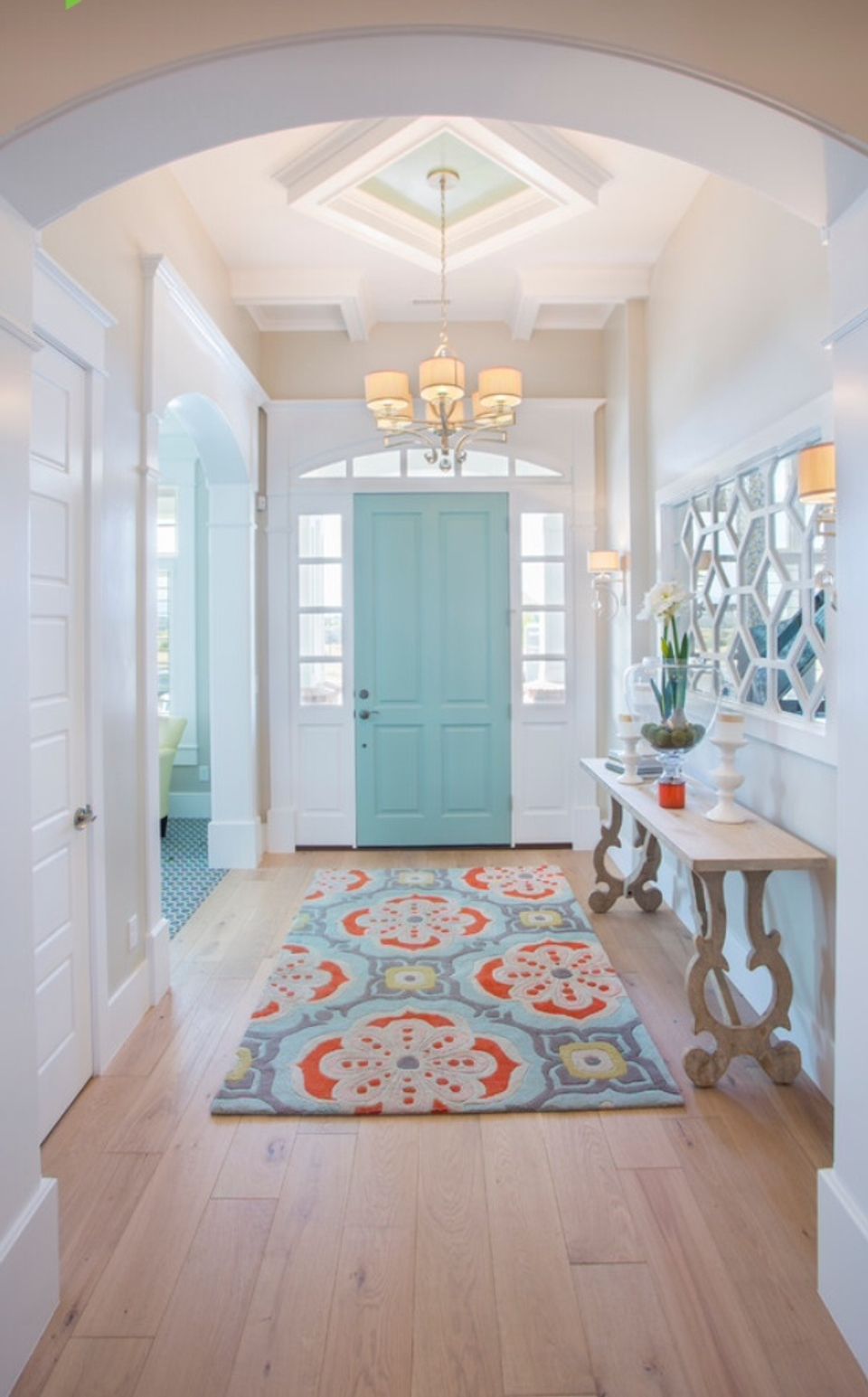 Bright coastal entryway with mint green door, arched ceiling, geometric patterned runner, and natural wood accents