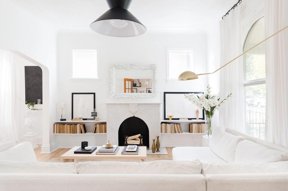 Minimalist Scandinavian living room with black faux fireplace, white walls, and natural wood accents